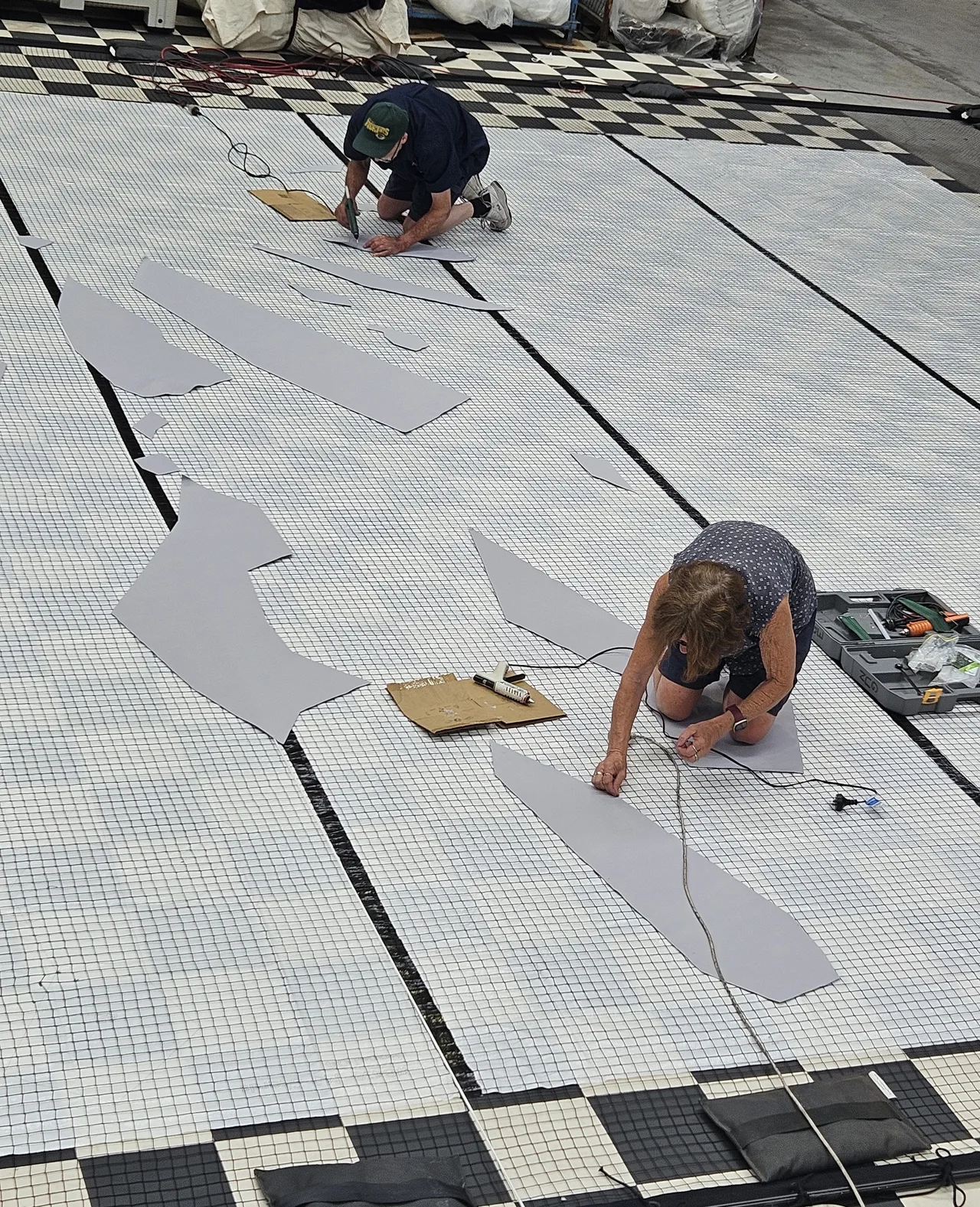 Crew cutting and fitting vinyl applique on the show floorcloth